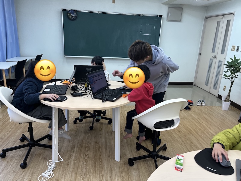 指導する先生とプログラミングを楽しむ子供たち